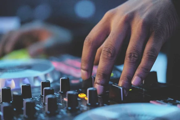 Imagem coloridas mostram mãos de DJ tocando em lugar que parece ser uma festa - Metrópoles