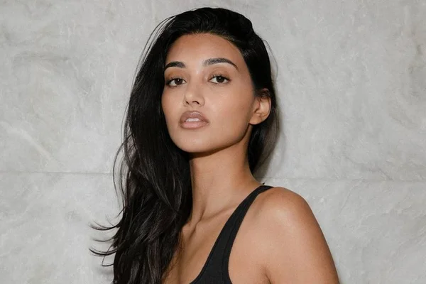 Foto colorida da modelo Neelam Gill de blusa preta e cabelo solto - Metrópoles