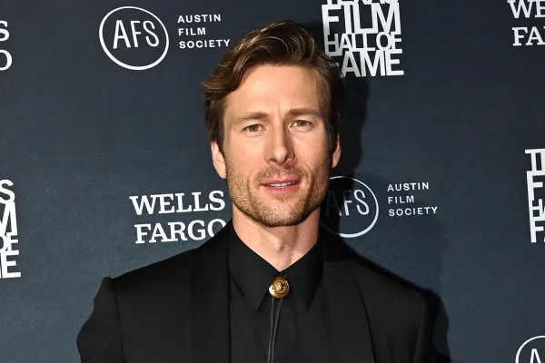 Na imagem colorida, Glen Powell posa em tapete vermelho com terno - Metrópoles