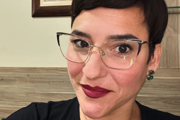 Simone Gutierrez posa, sorridente, de óculos - Metrópoles