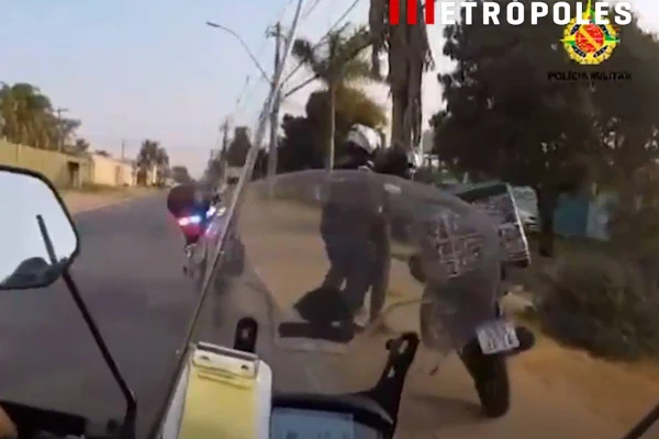 Foto colorida de policias em moto prendendo motociclista