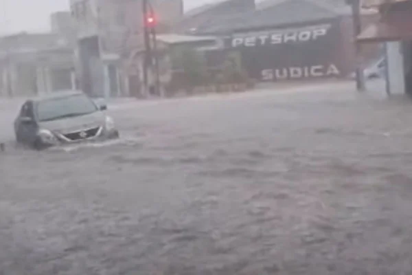 Imagem colorida de rua alagada com carro boiando