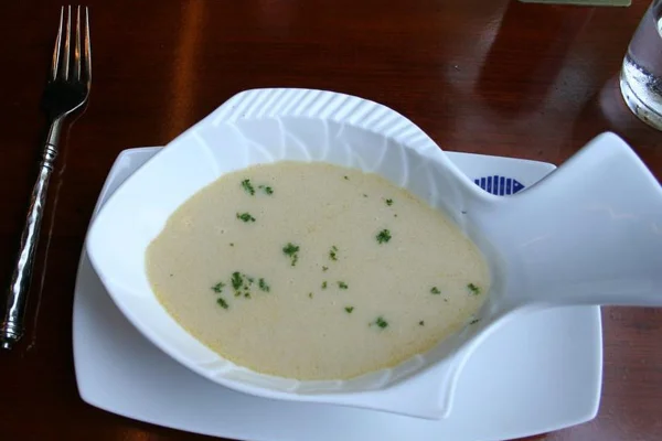 Sopa de peixe cremosa em travessa branca imitando forma do animal sob mesa de madeira escura - Metrópoles