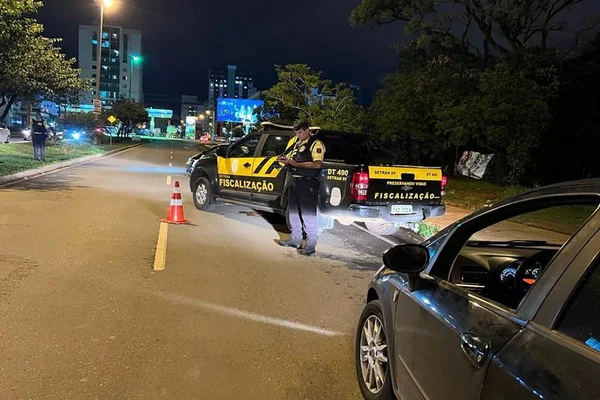 foto colorida. viatura do detran com agente parado na frente