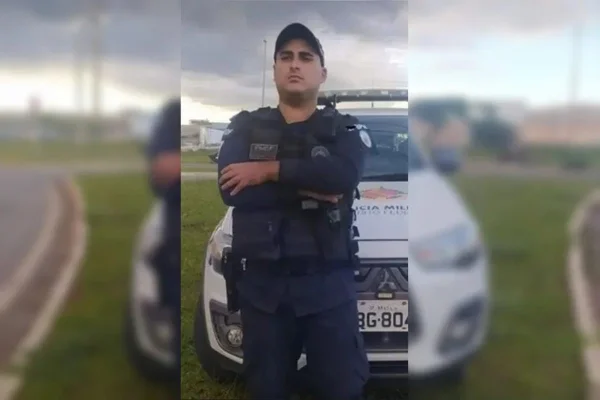 Policial militar em frente a viatura