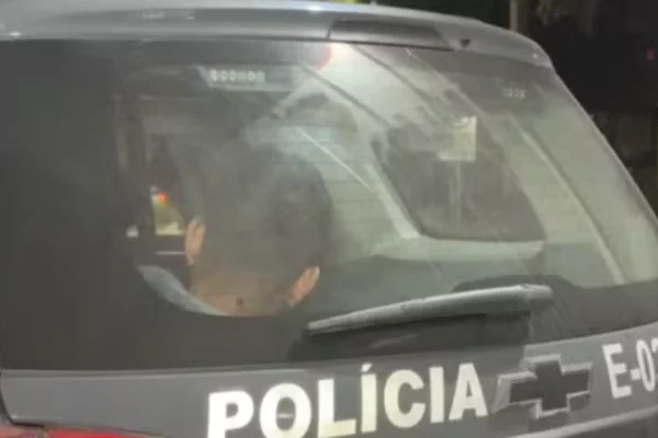 Imagem colorida de um homem preso no compartimento de presos de uma viatura da polícia - Metrópoles