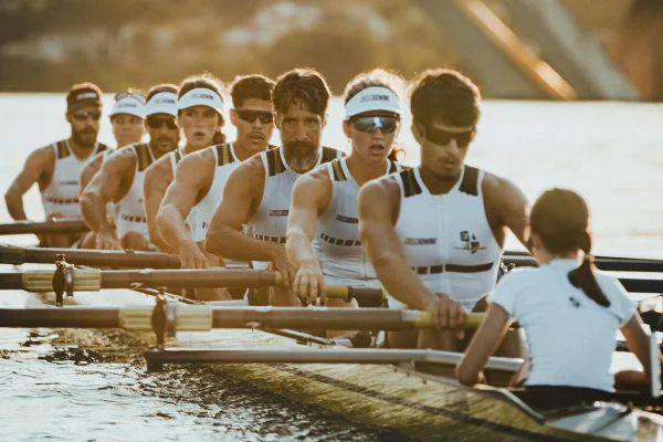 Foto colorida de grupo de pessoas remando em lago - Metrópoles