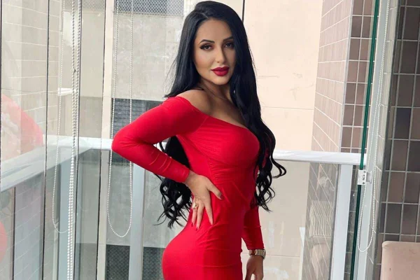 Foto colorida de irmã de Deolane usando vestido vermelho e com a mão na cintura - Metrópoles