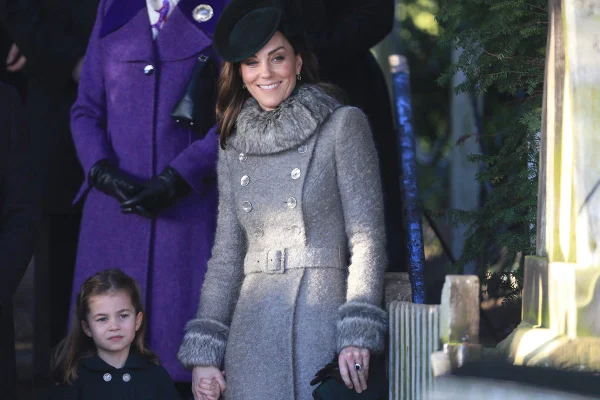 Menina segura a mão de mulher. As duas estão vestidas com roupas de frio, como casacos