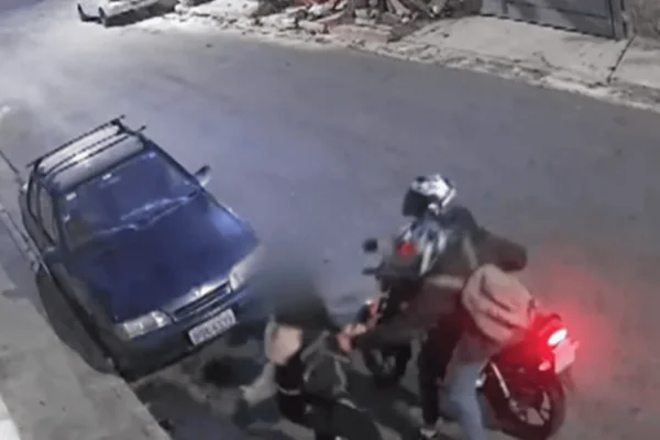 Imagem colorida de dois homens em uma moto assaltando uma jovem em uma via de SP - Metrópoles