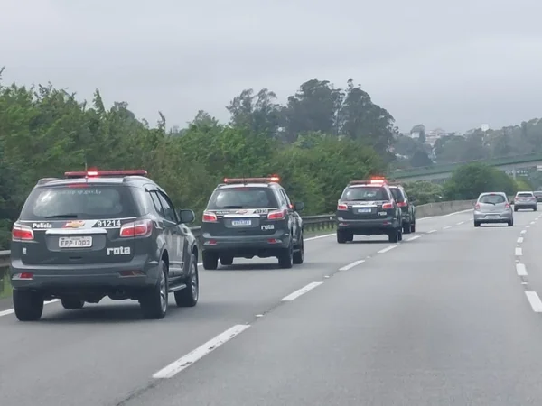 Imagem colorida mostra estrada com viatura da PM, cinzas, trafegando na pista da esquerda - Metrópoles