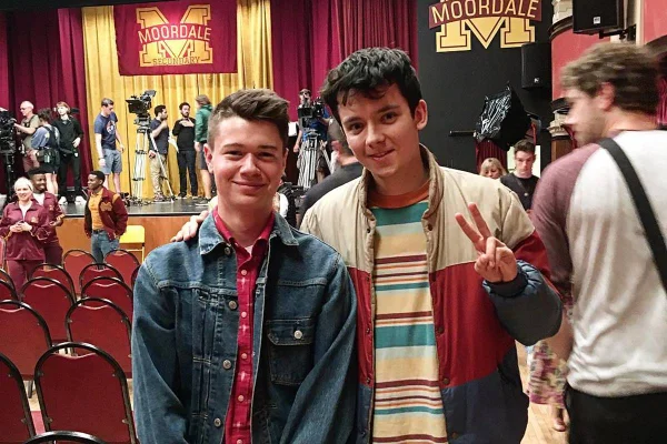 foto colorida de de dois jovens brancos de cabelos escuros posando lado a lado e sorrindo - metrópoles