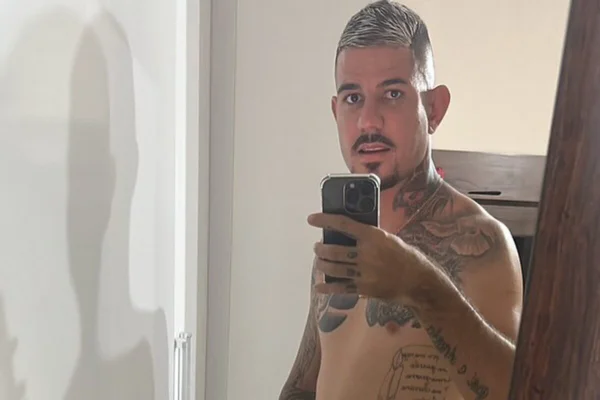 Homem branco, sem camisa, com corpo taruado, cabelo descolorido e cavanhaque preto - Metrópoles