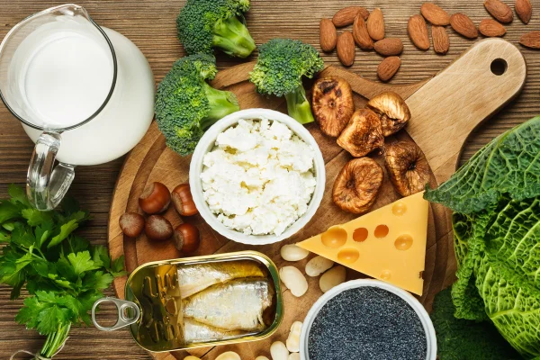 Alimentos ricos em cálcio como sardinha, feijão, figos secos, amêndoas, queijo cottage, avelãs, folhas de salsa, semente de papoula azul, brócolis, couve italiana, queijo, leite