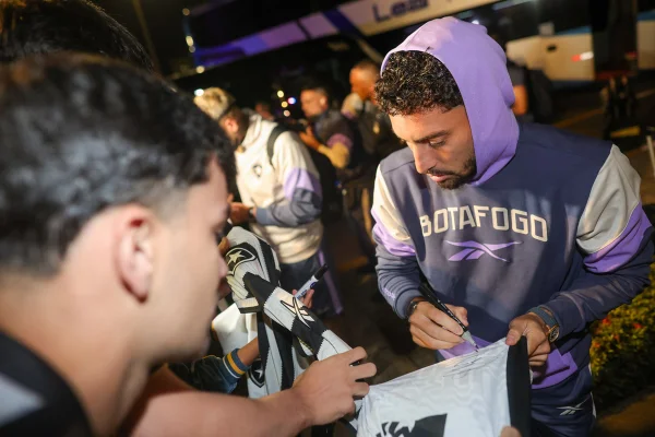 Foto de Alex Telles autografando camisa do Botafogo - Metrópoles