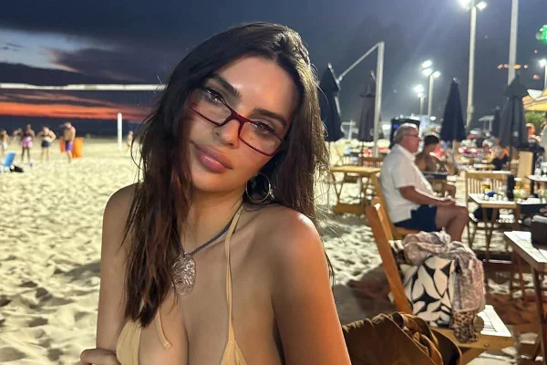Imagem colorida da atriz Emily Ratajkowski usando óculos, em praia no Rio - Metrópoles