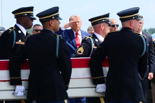 O presidente dos EUA, Donald Trump (ao centro), presta continência enquanto membros de uma equipe de transporte do Exército dos EUA conduzem o caixão de traslado — coberto pela bandeira americana