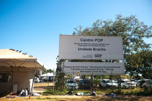 Casa e placa grande com texto em frente a grade