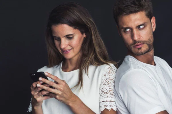 Imagem colorida de homem observando parceira mexer no celular