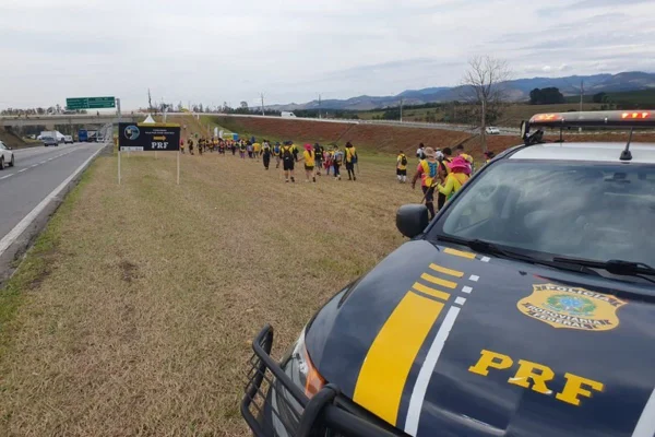 Imagens mostram romeiros à beira da estrada, acompanhados por viatura da PRF