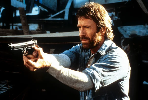 Chuck Norris aponta uma arma em uma cena do filme 'Herói e o Terror', de 1988