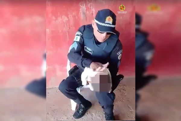 policial militar sentado e segurando uma criança de 3 meses nos braços