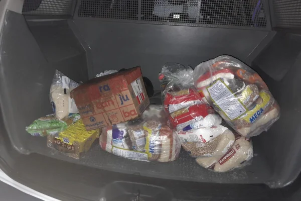 três cestas básicas no bagageiro de uma viatura