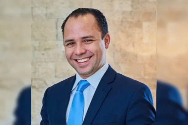 Homem branco com terno e gravata azul sorrindo