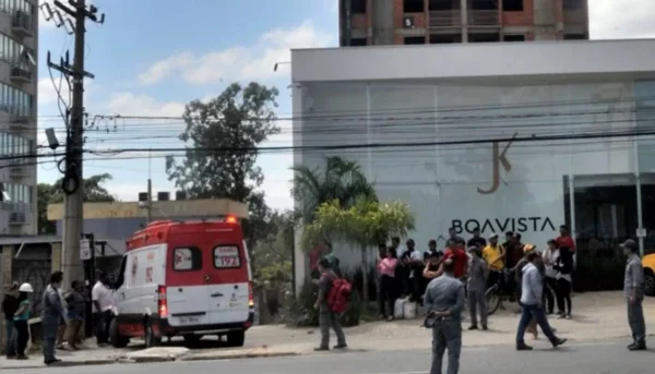 foto de uma ambulância do samu em frente a um prédio com uma aglomeração de pessoas
