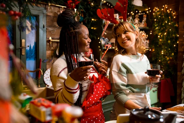 Duas mulheres sorrindo em cozinha durante confraternização de Natal - Metrópoles