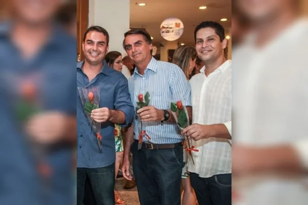 O senador Flávio Bolsonaro, o ex-presidente Jair Bolsonaro e o empresário Alexandre Santini seguram rosas na festa de inauguração da franquia da Kopenhagen que o senador havia inaugurado na Barra da Tijuca