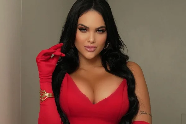 Foto colorida de Emily Garcia. Ela é branca e veste uma roupa vermelha - Metrópoles