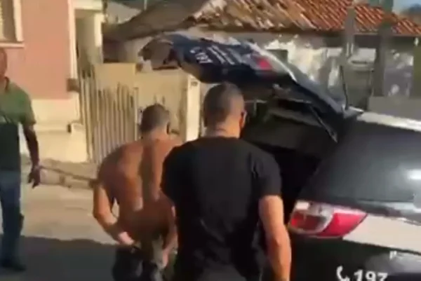 Imagem colorida de homem preso sendo levado para viatura policial. Metrópoles
