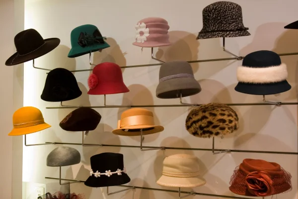 Diversos chapéus estão dispostos sob uma parede com suporte interno apoiando os chapéus com variadas cores e estampas.