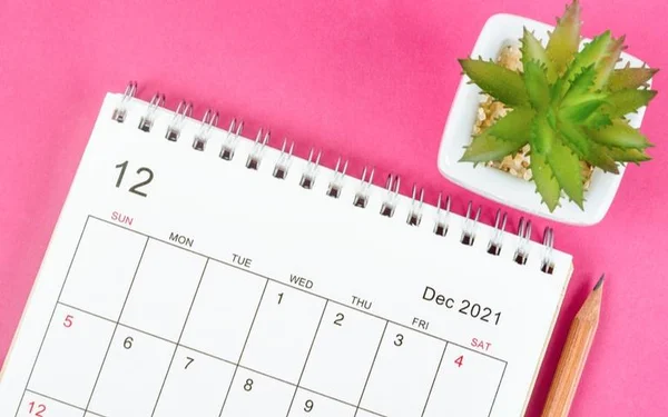 Na foto, um Calendário branco em fundo rosa