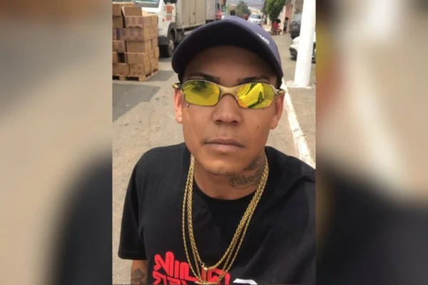 Foto colorida de homem com óculos colorido e boné.