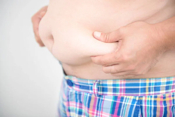 Imagem colorida de pessoa segurando própria barriga com as mãos - Metrópoles