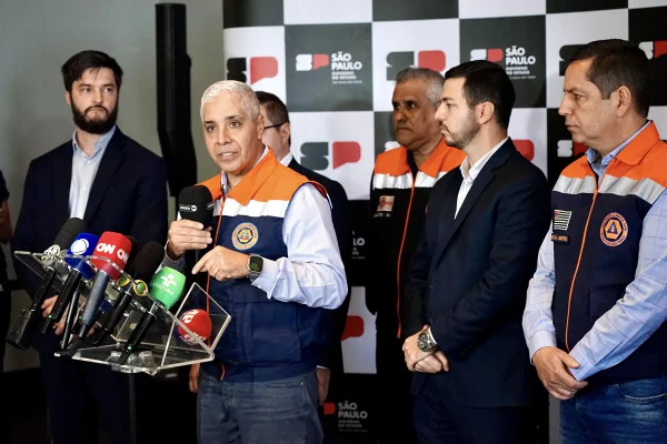 imagem colorida mostra agentes da defesa civil em entrevista coletiva