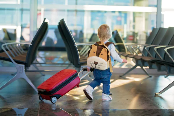 criança com mala e uma mochila nas costas no aeroporto