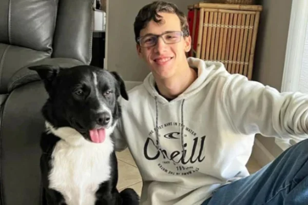 Foto colorida de um jovem com cachorro - Metrópoles