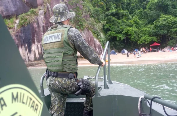 Policial em barco em frente a uma praia - Metrópoles