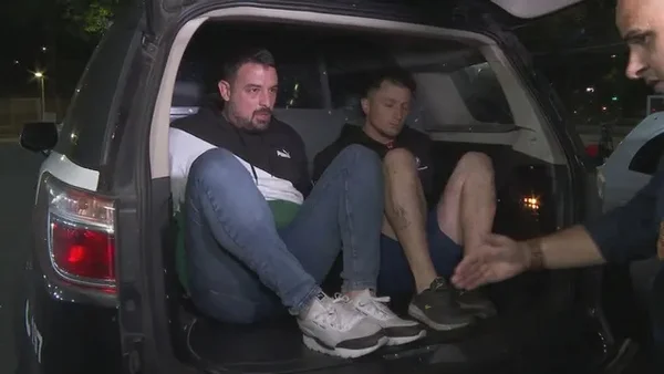 Imagem colorida mostra torcedores argentinos do San Lorenzo preso por racismo em partida contra o São Paulo. Eles estão dentro de uma viatura policial, na parte de trás - Metrópoles