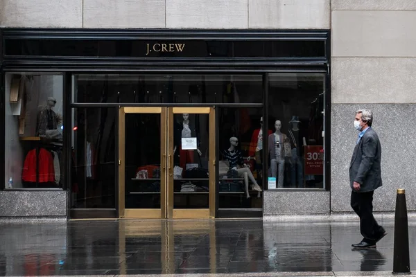 Homem de máscara passando em frente a loja da J.Crew