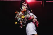 Lily Allen posa sorridente com um buquê de flores que ganhou
