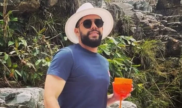 Foto colorida de Willian Mulezini Santana, de chapéu branco, camiseta azul e óculos escuros; ele tem cavanhaque e está sorrindo