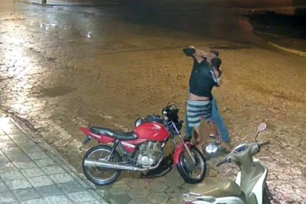 Foto colorida de momento em que vítima luta tentando desarmar homem durante briga.