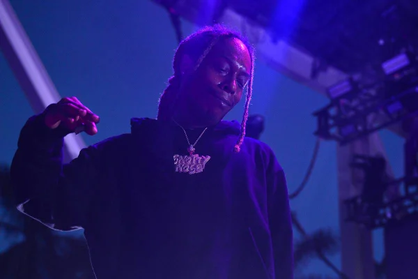 foto azulada de homem negro de dreads e moletom preto em palco - metrópoles