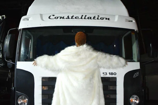 Foto colorida de Karol Conká reproduzindo meme pendurada em caminhão - Metrópoles