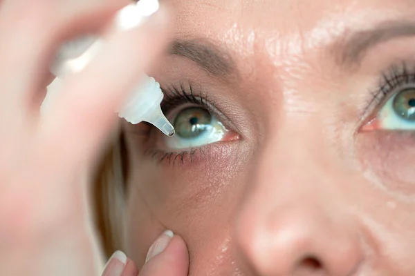 Imagem colorida de mulher pingando colírio em um dos olhos