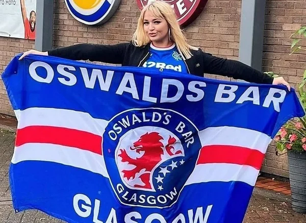 Lana Wolf, famosa torcedora de time escocês, com bandeira e uniforme do Rangers. Ela foi espancada e estrangulada por ex - Metrópoles
